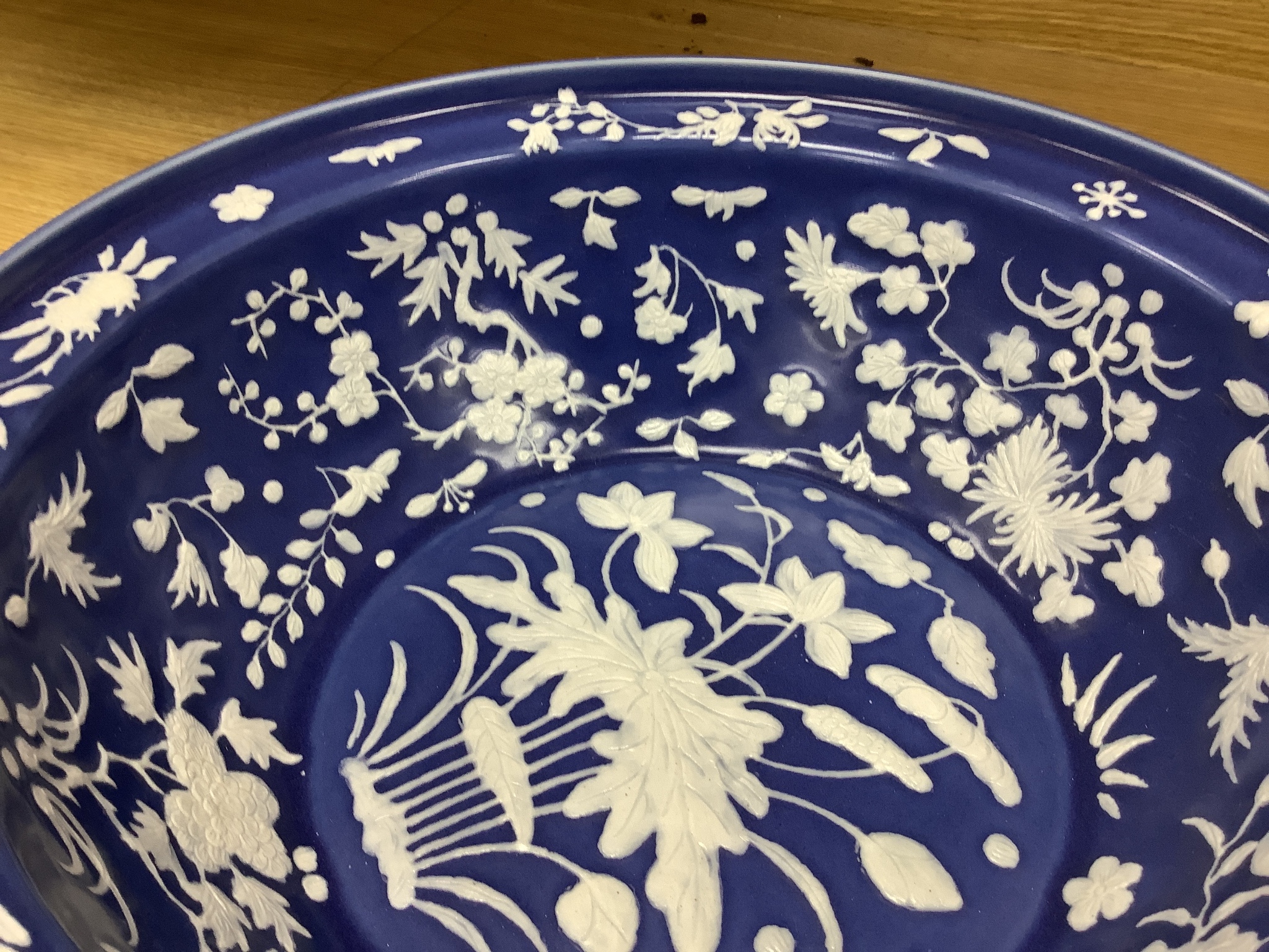 A large Chinese blue and white porcelain basin, lightly relief moulded with plants, 40cm